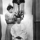A woman using a perming machine made by Messrs Gallia.